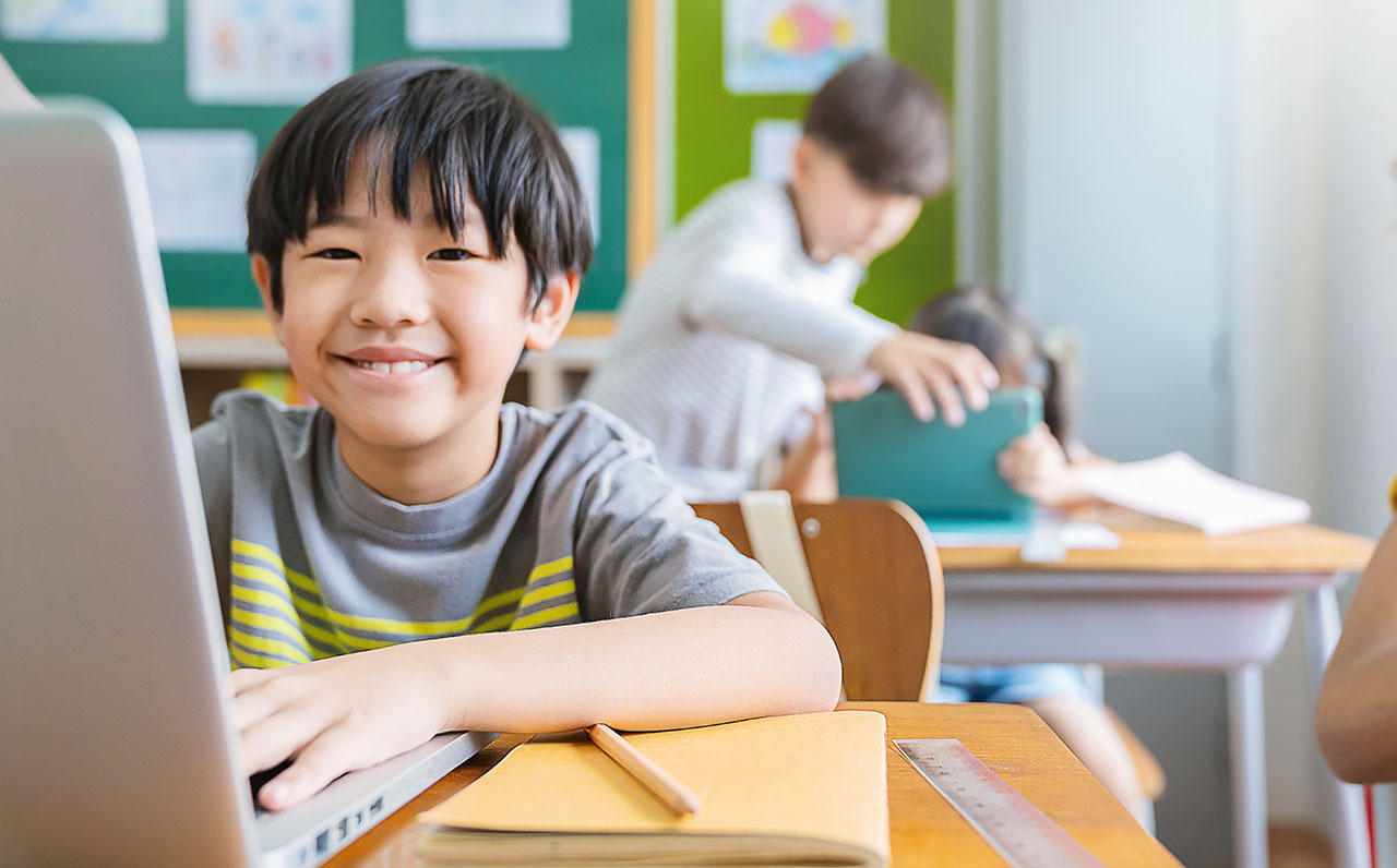 Portrait of Asian little boy using computer to learn lessons in