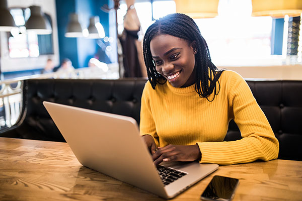 Human and technology. Young african woman typing on laptop, text